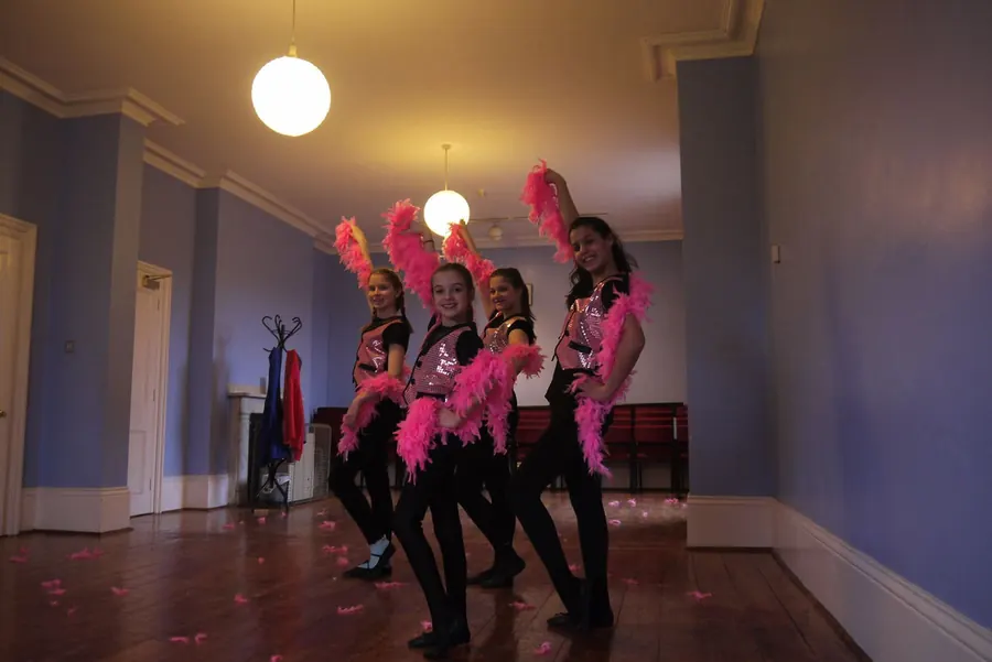 Pupils performing a feather fan routine on stage in Harlow