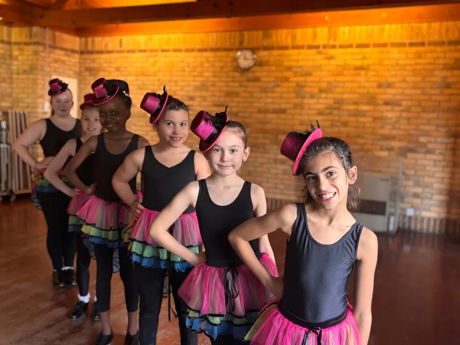Junior tap pupils in pink top hats and rainbow tutus in the Harlow dance studio