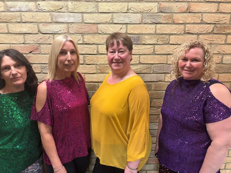 Adult dance class members in colourful sequinned tops in the Harlow dance studio